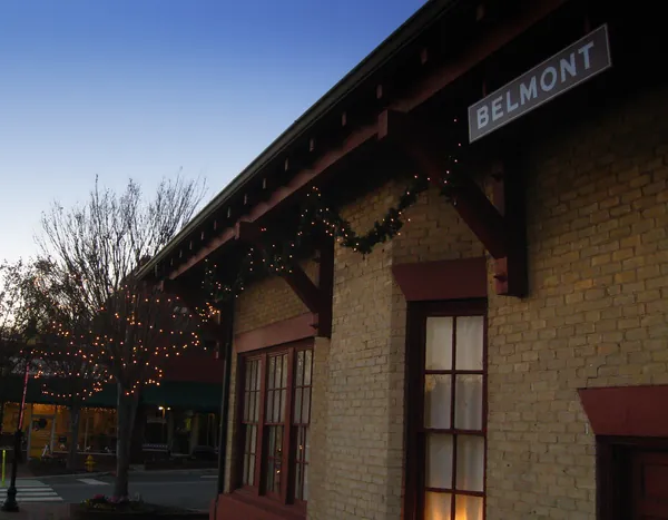 The old Belmont train depot at dusk, with a BELMONT sign and holiday lights