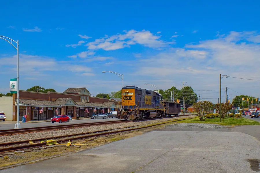 A CSX train passing storefronts in Stanley, North Carolina